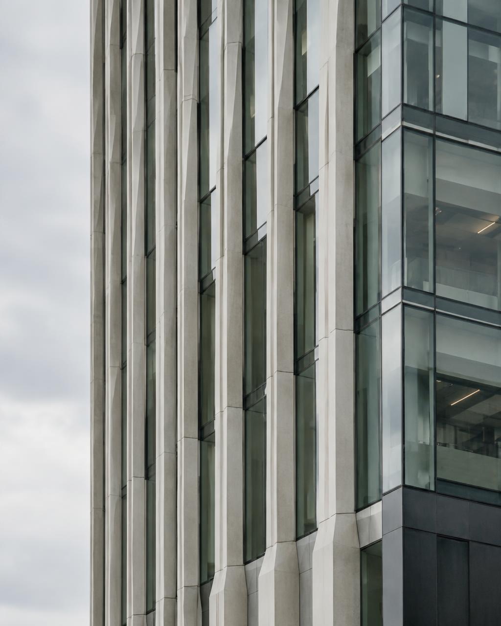Illustrative office facade with pale concrete fins and glass under an overcast sky